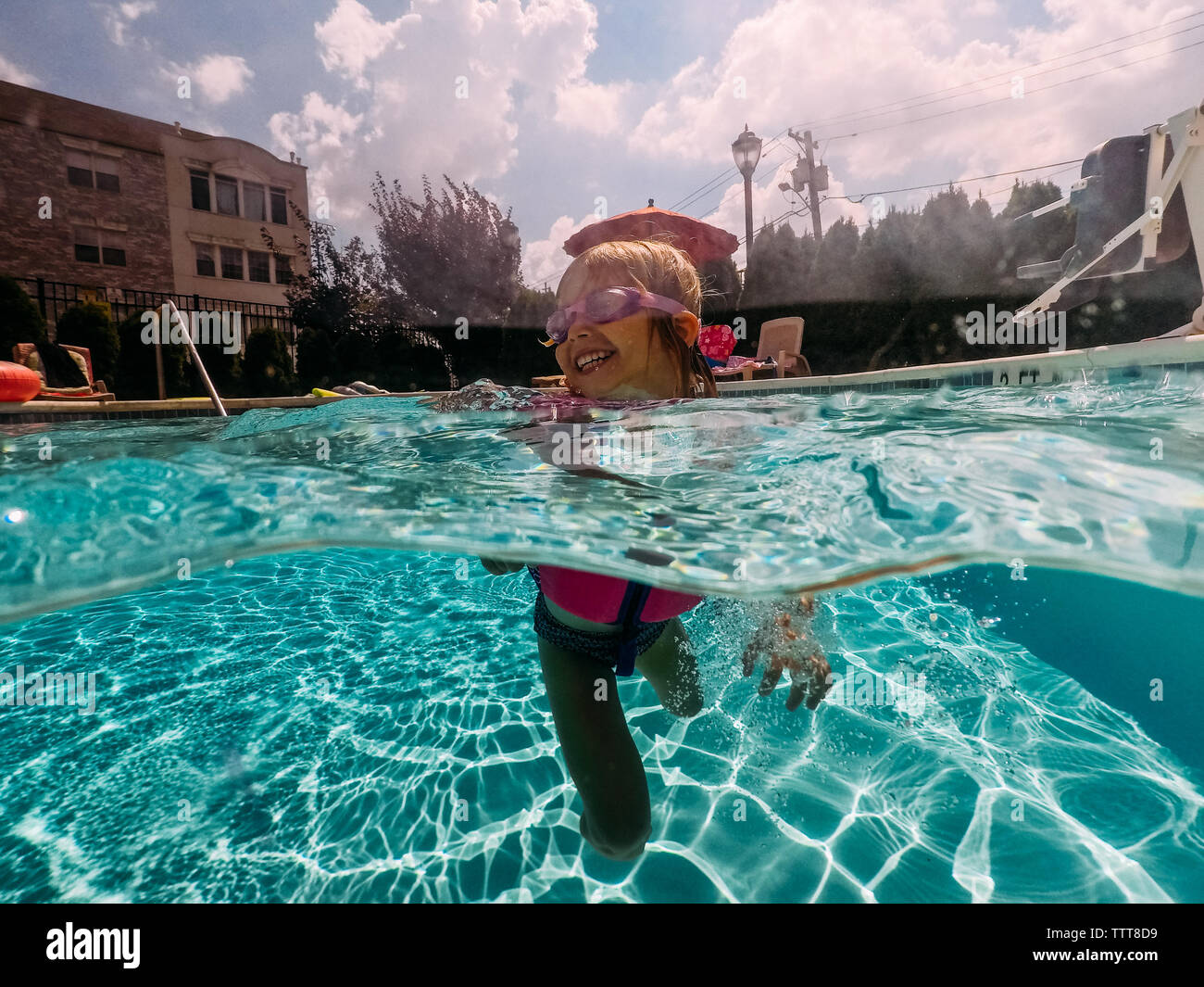 Bambina felice di nuoto con gli occhiali di protezione in piscina Foto Stock