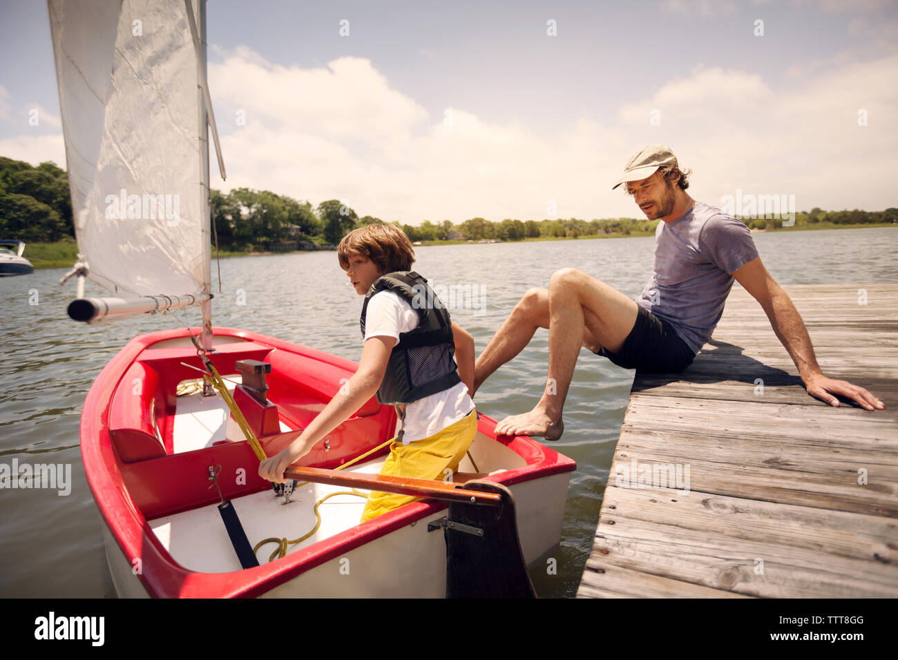 Padre e Figlio con la barca nel lago contro sky Foto Stock