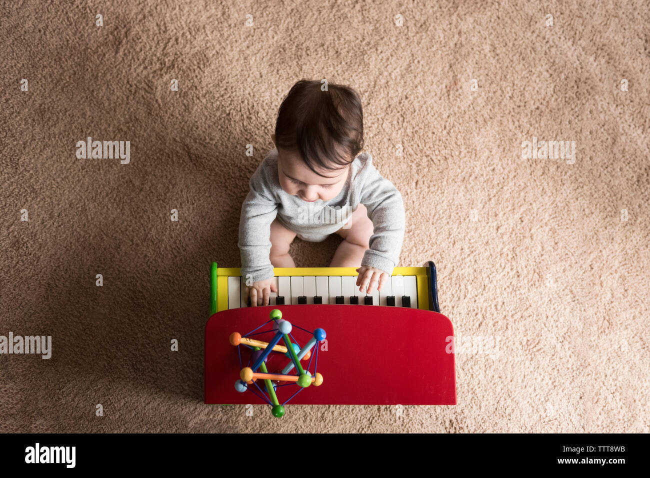 Vista aerea del bambino suonare il pianoforte giocattolo sul tappeto a casa Foto Stock