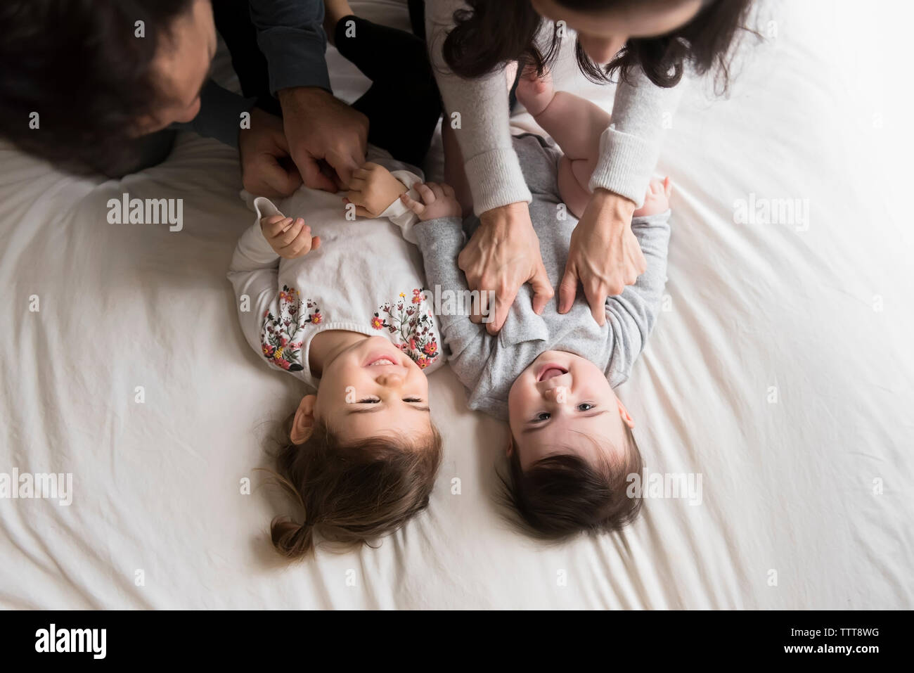 Angolo di alta vista di giocoso solletico dei genitori di bambini su letto di casa Foto Stock