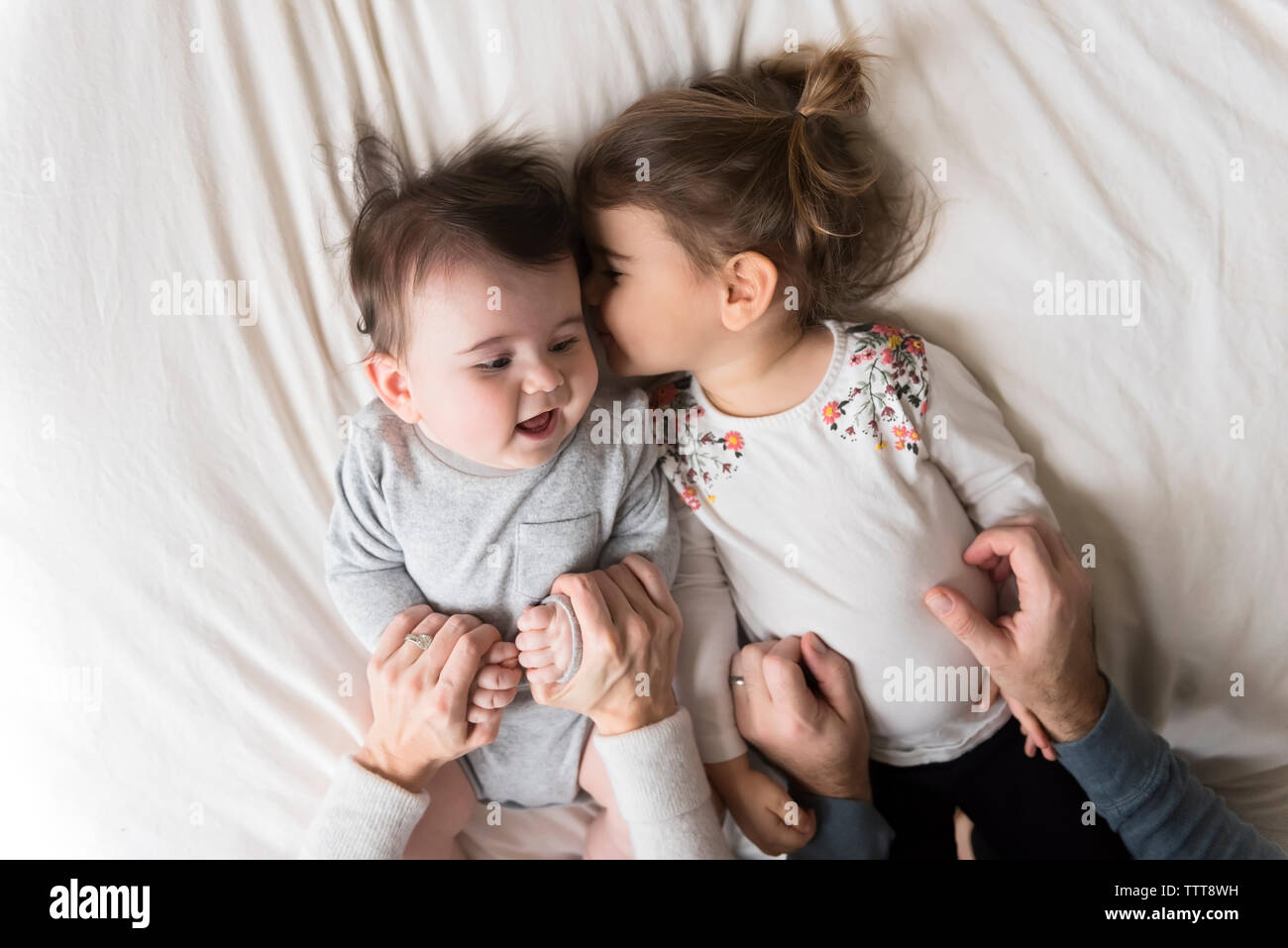 Tagliate le mani dei genitori di bambini di contenimento sul letto di casa Foto Stock