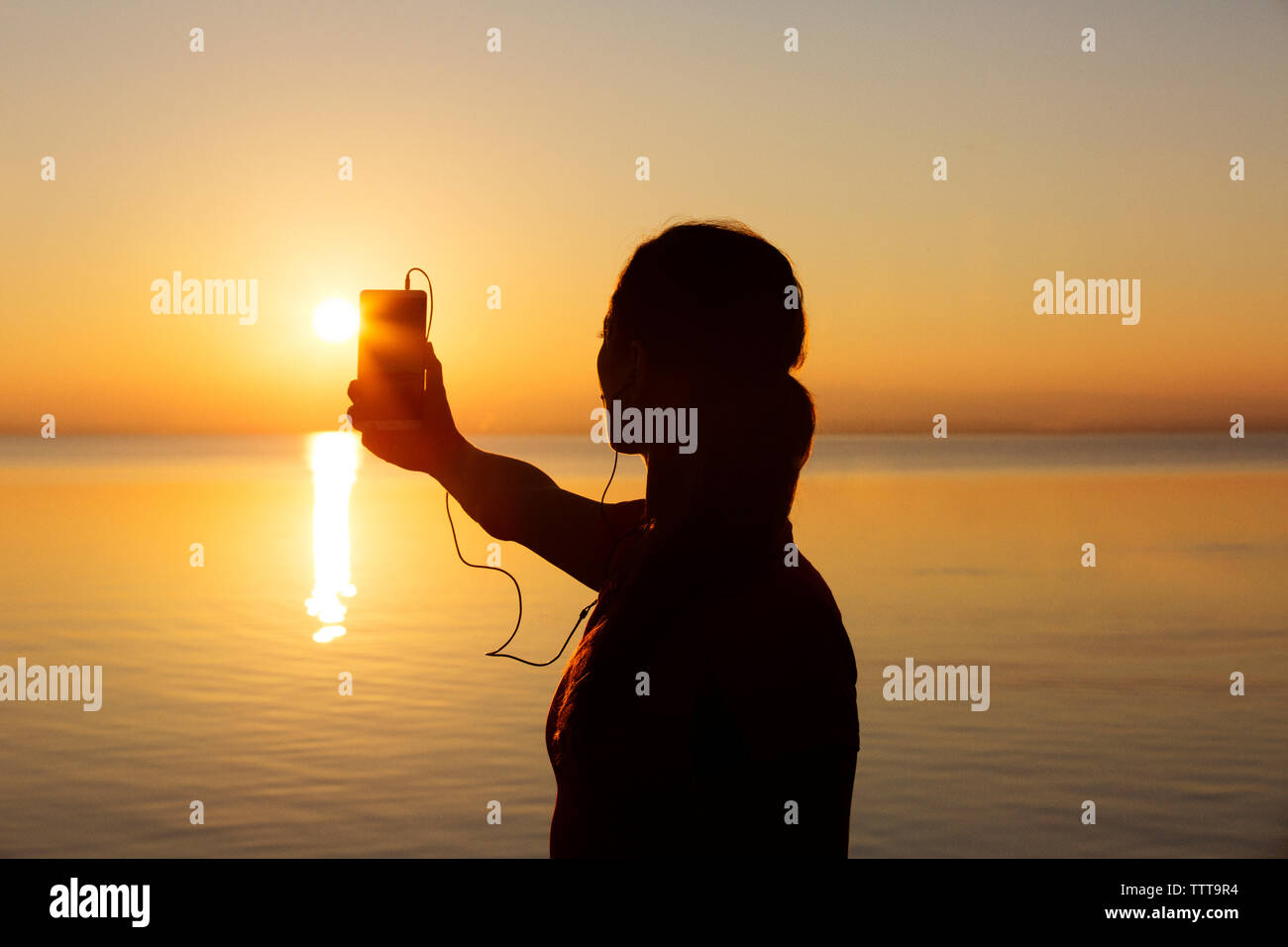 Silhouette donna orizzonte fotografare durante il tramonto Foto Stock