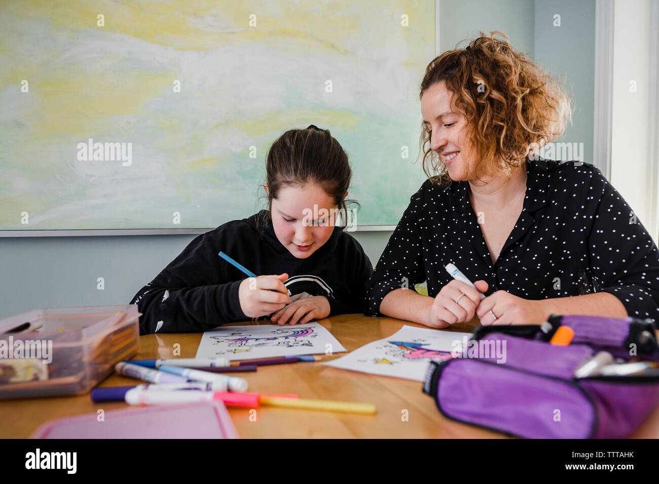 Figlia di madre disegni da colorare sul tavolo a casa Foto Stock