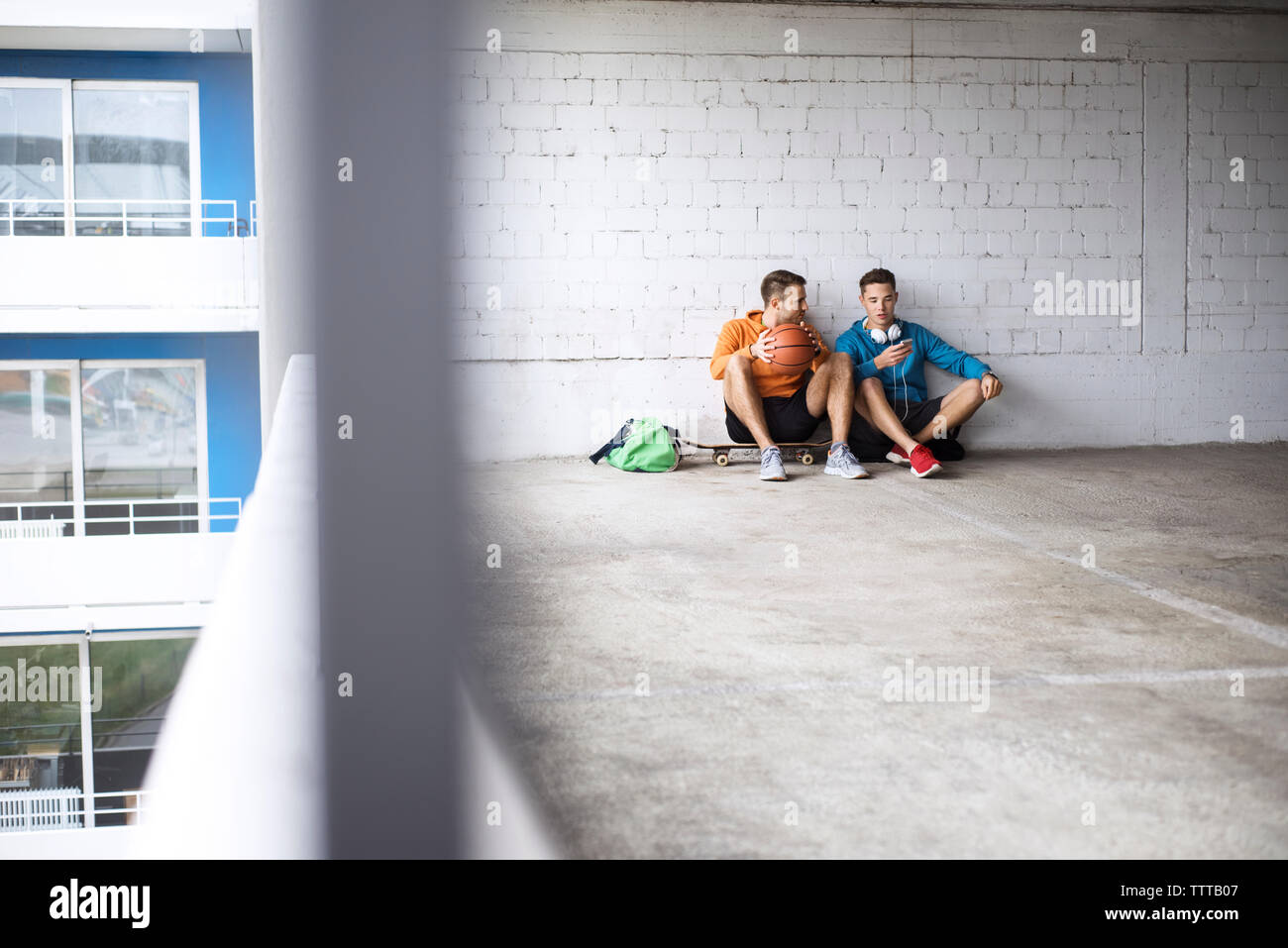 Amici di sesso maschile con basket e skateboard in parcheggio Foto Stock
