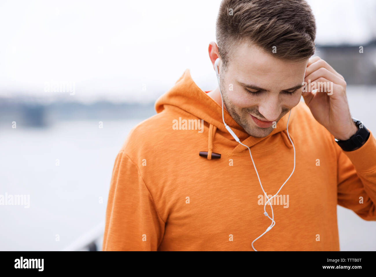 Sorridente atleta maschio ascoltando musica all'aperto Foto Stock