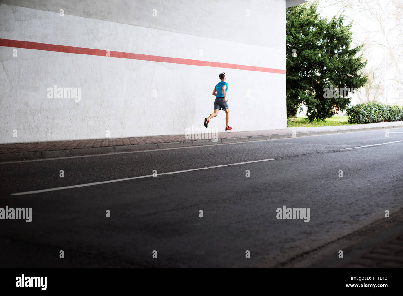 Vista posteriore dei maschi di atleta che corre sul marciapiede di strada Foto Stock