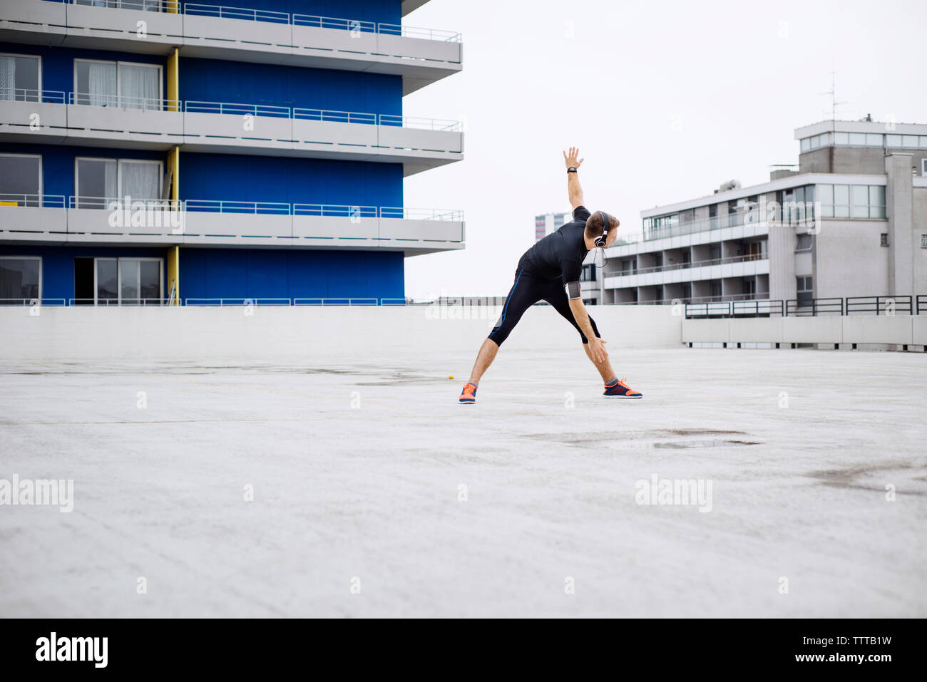 Atleta maschio facendo esercizio di riscaldamento sulla terrazza Foto Stock