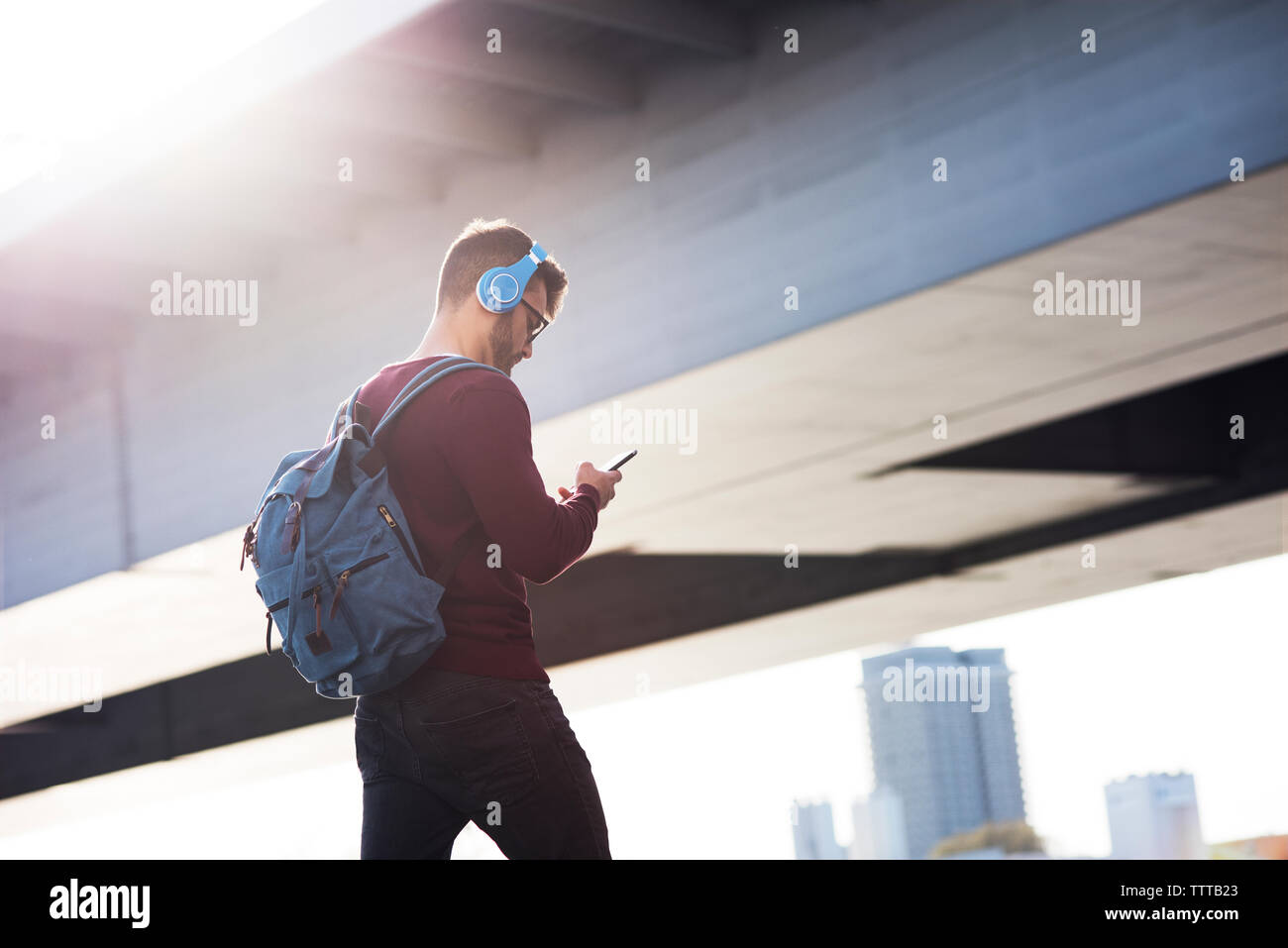 Giovane uomo utilizzando il telefono mentre si cammina su bridge Foto Stock