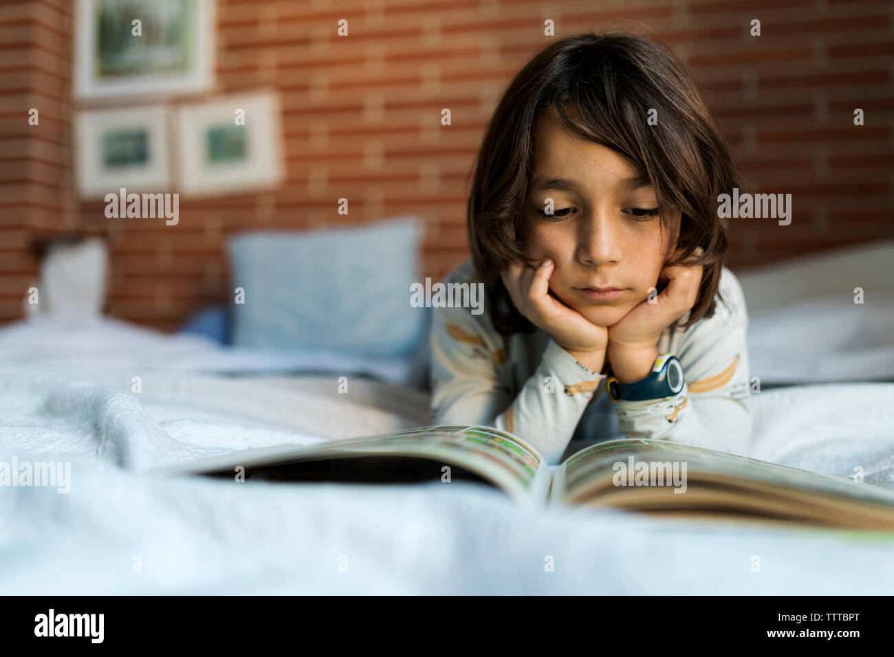 Kid leggendo un libro la posa sul letto Foto Stock