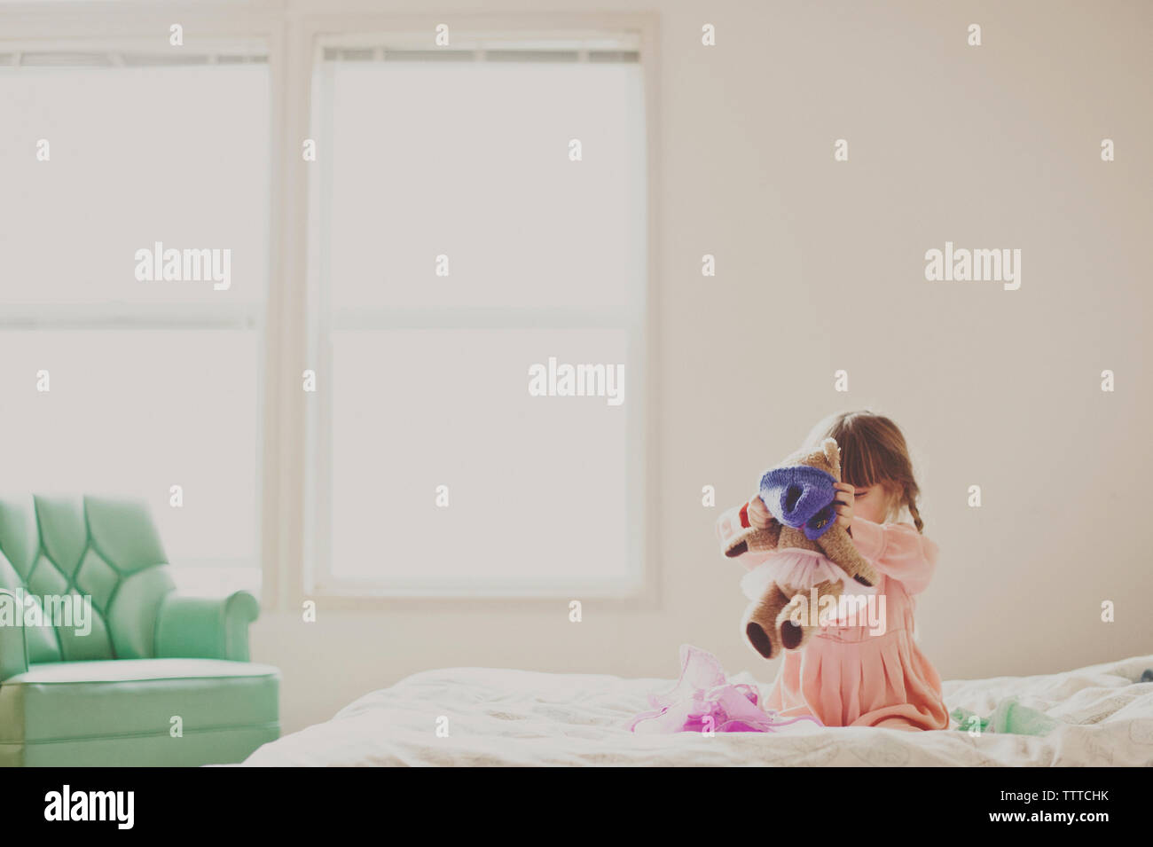 Ragazza che gioca con Teddy bear in camera da letto a casa Foto Stock