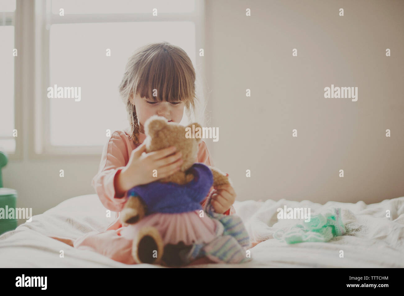 Ragazza che gioca con Teddy bear sul letto Foto Stock