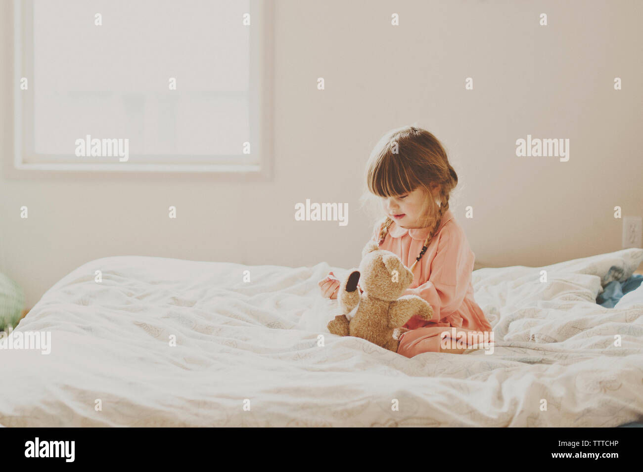 Carina ragazza che gioca con Teddy bear sul letto Foto Stock