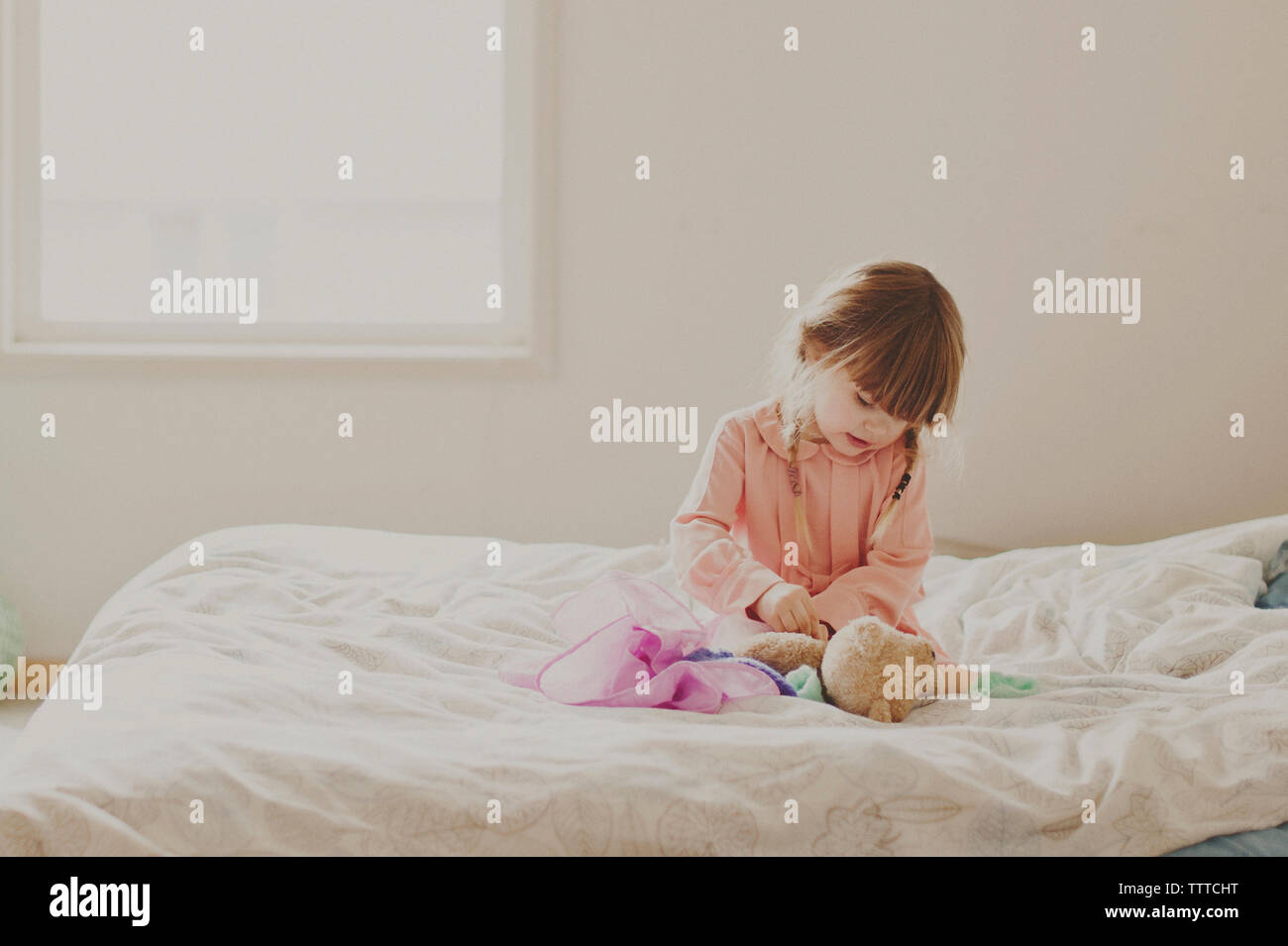 Ragazza che gioca con Teddy bear sul letto Foto Stock
