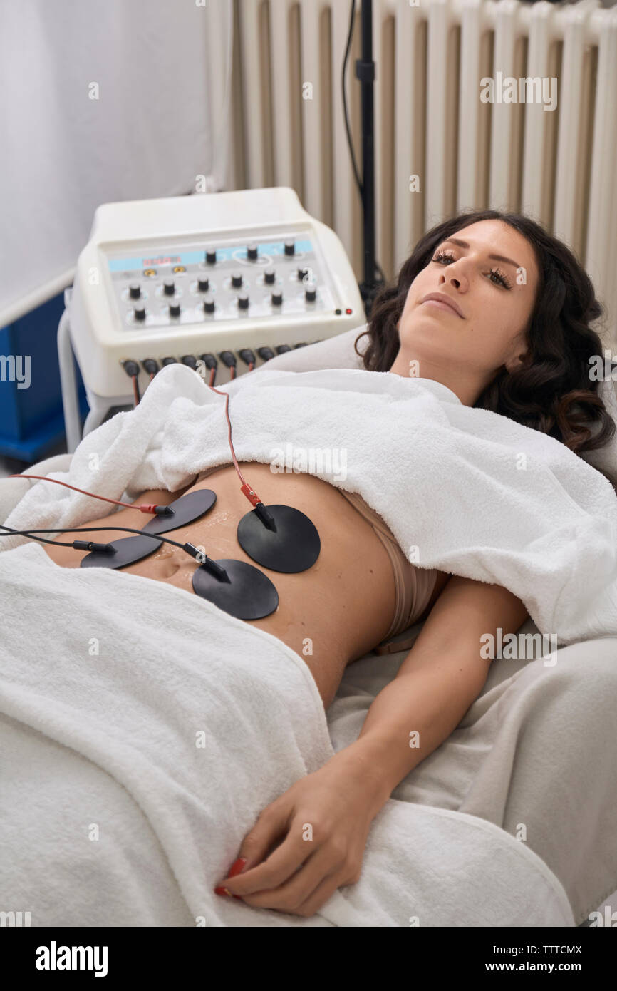 Angolo di Alta Vista del paziente avente elettrodi di terapia fisica mentre giacenti presso la clinica medica Foto Stock