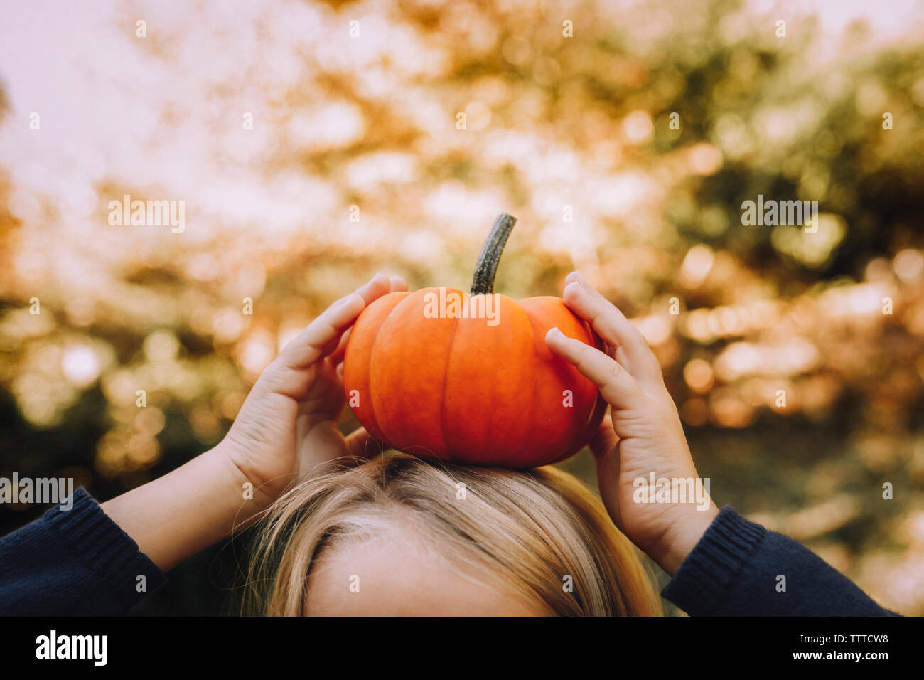 Immagine ritagliata della ragazza di zucca di bilanciamento sulla testa Foto Stock