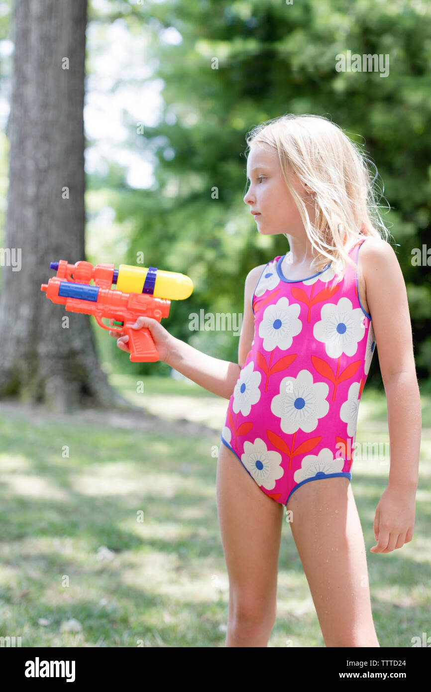 Ragazza giovane con un watergun in un costume da bagno Foto Stock