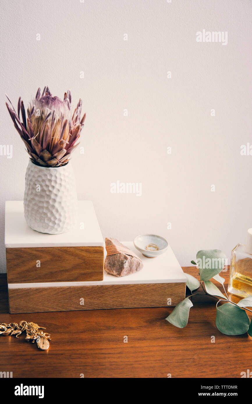 Angolo di alta vista del vaso di fiori con gioielli e prodotto di bellezza sul tavolo di legno Foto Stock