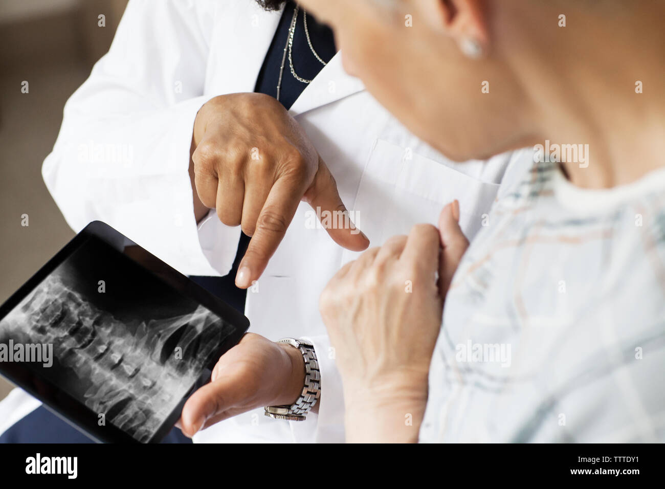 Sezione mediana del medico che mostra immagine a raggi X al paziente in ospedale Foto Stock