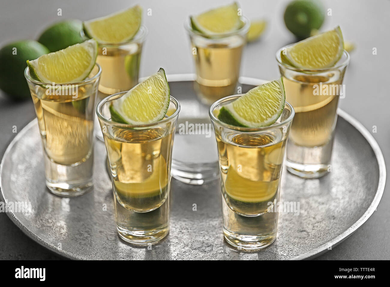 Colpi di tequila oro con fettine di lime e sale su un vassoio Foto Stock