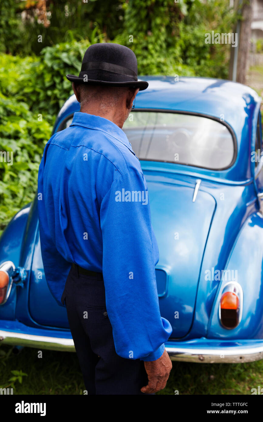 Giamaica, Port Antonio. Giuseppe " polveri " Bennett del Mento Band, il Jolly Boys in piedi di fronte a un vintage auto blu. Foto Stock