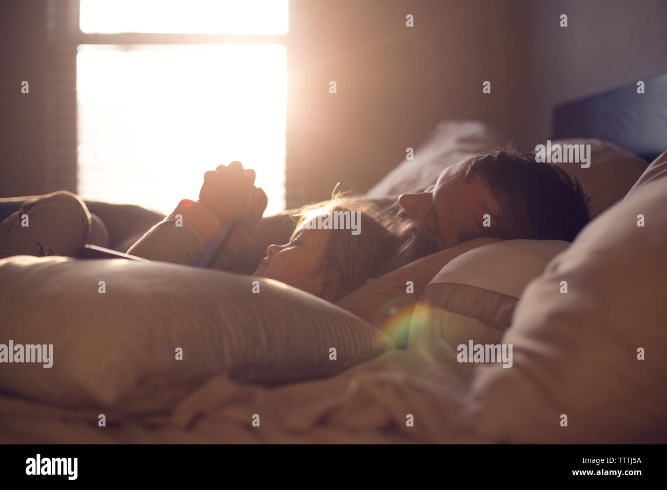 Genitore e bambino condividono una pigra mattina nella splendida e sognanti luce. Foto Stock