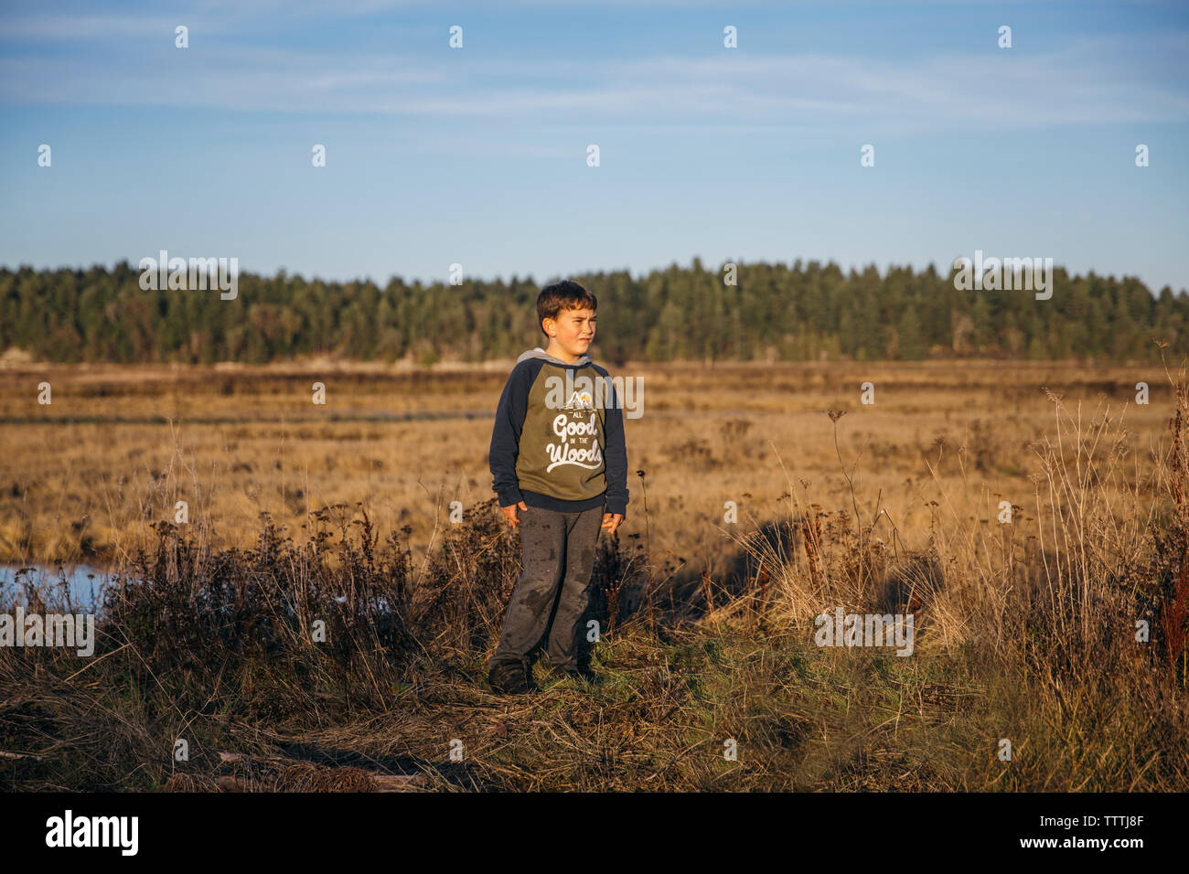 Ragazzo in piedi in un campo con un paesaggio naturale Foto Stock
