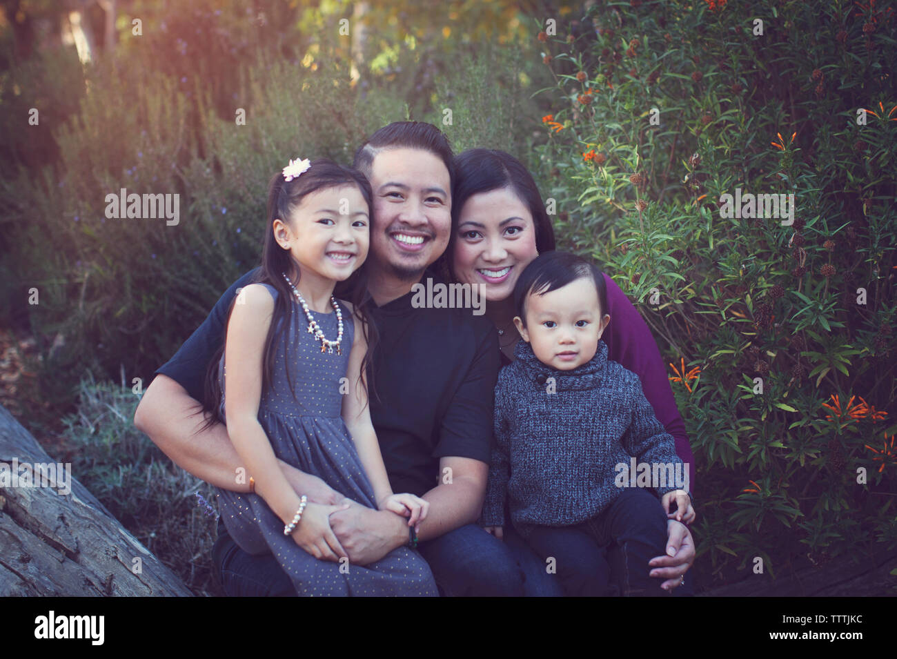 Ritratto di famiglia felice contro piante in posizione di parcheggio Foto Stock