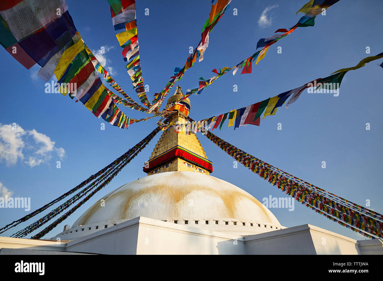 Basso angolo vista di Boudhanath stupa con colorati bandiere di preghiera contro il cielo blu Foto Stock