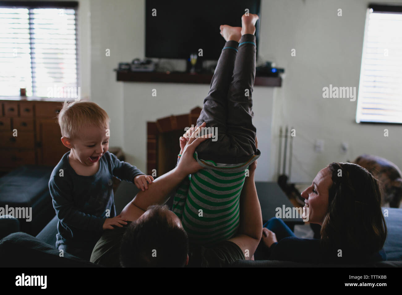 Genitori felici giocando con i bambini sul divano di casa Foto Stock