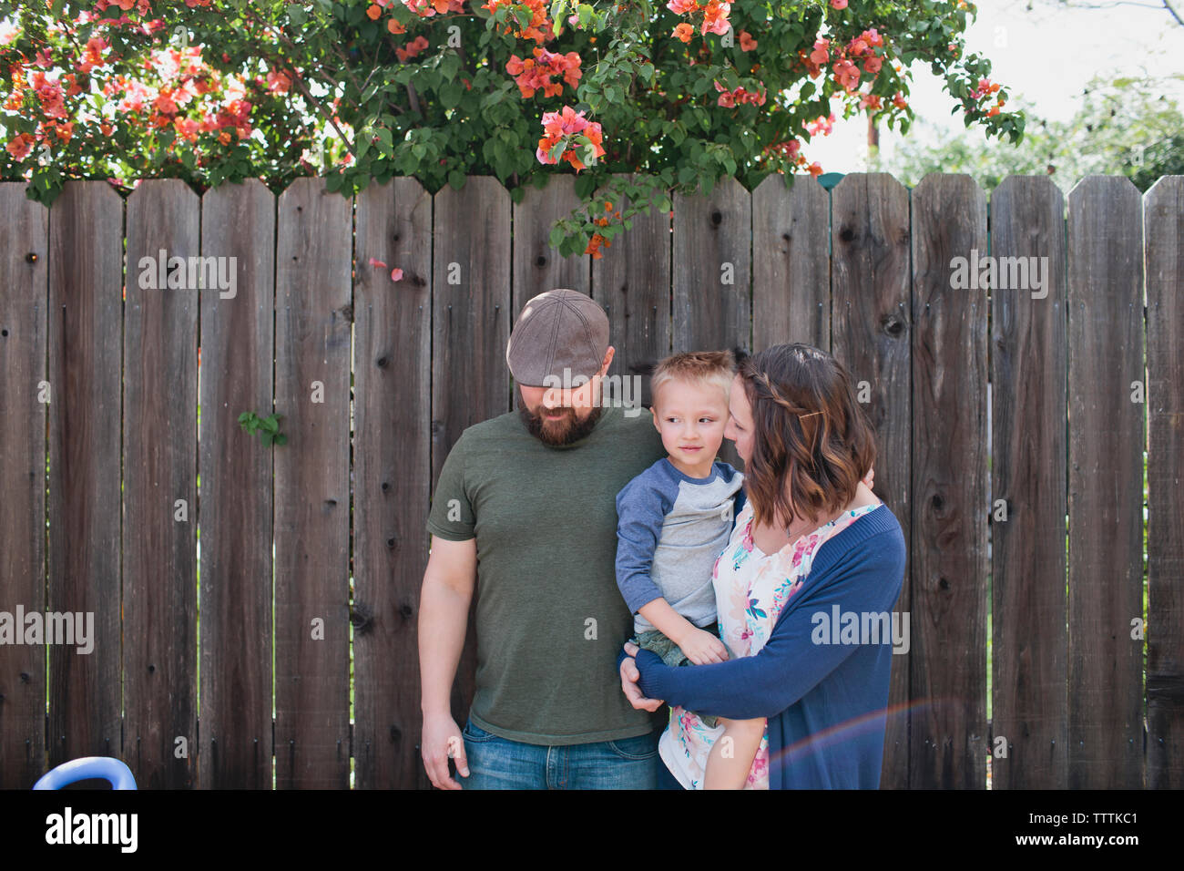 La madre che porta il figlio mentre sta in piedi con il marito dal recinto nel cortile posteriore Foto Stock