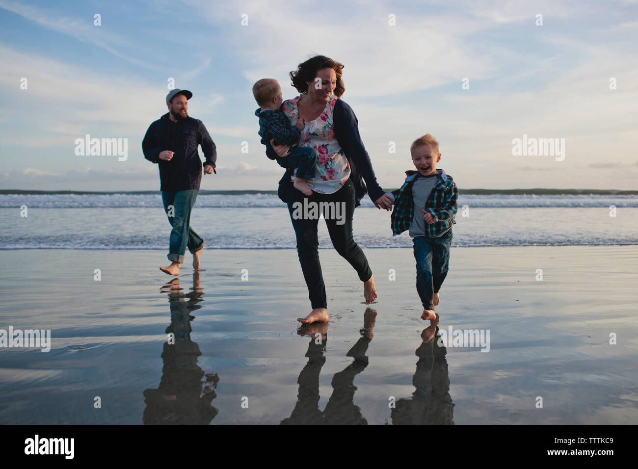 Famiglia allegra in esecuzione in riva al mare Foto Stock