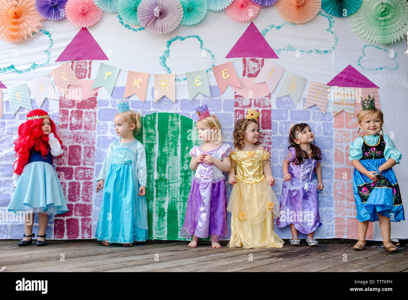 Cute ragazze in piedi contro la pittura del castello durante la principessa party Foto Stock