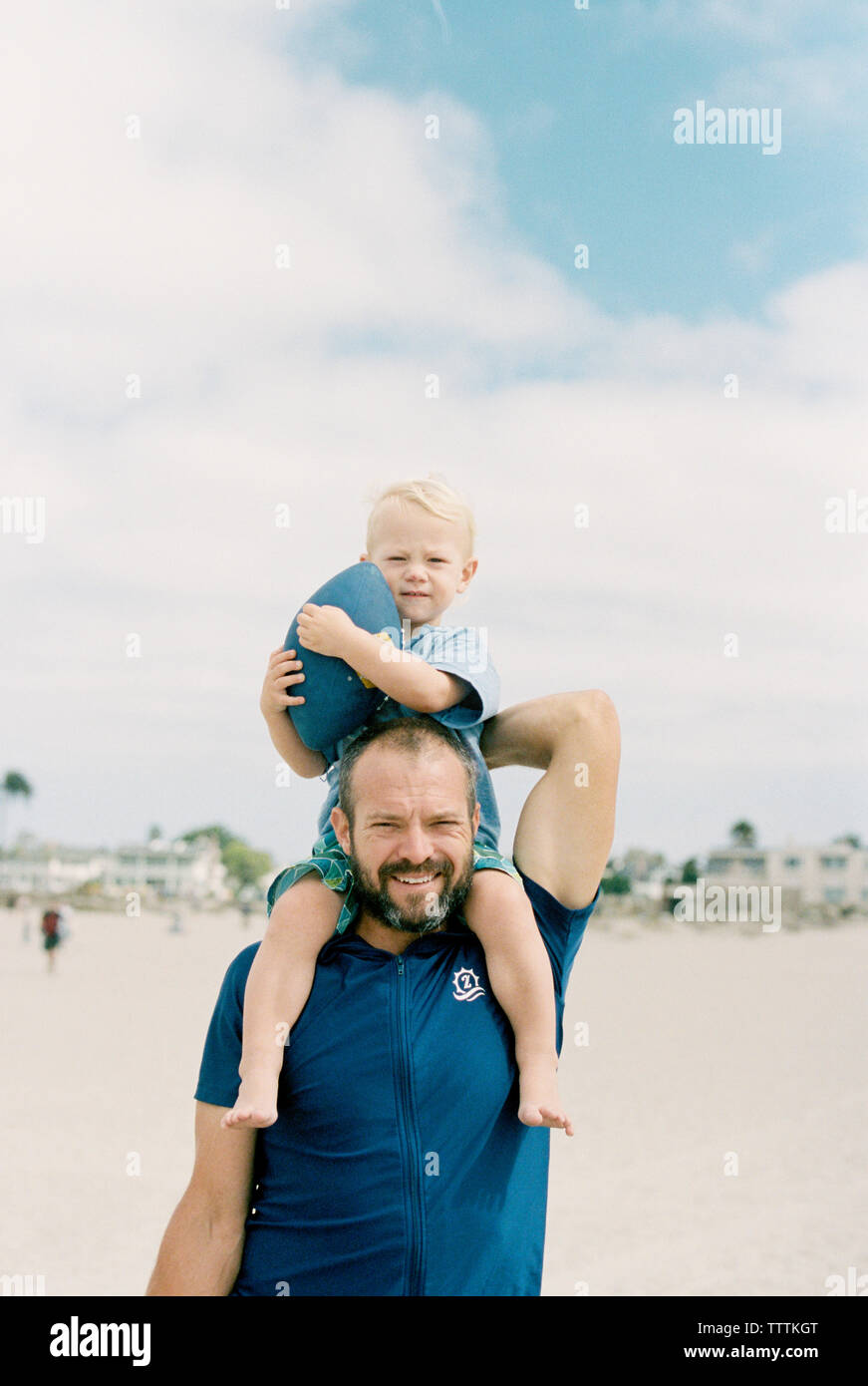 Ritratto di padre figlio che porta sulle spalle mentre si sta in piedi in spiaggia contro sky Foto Stock