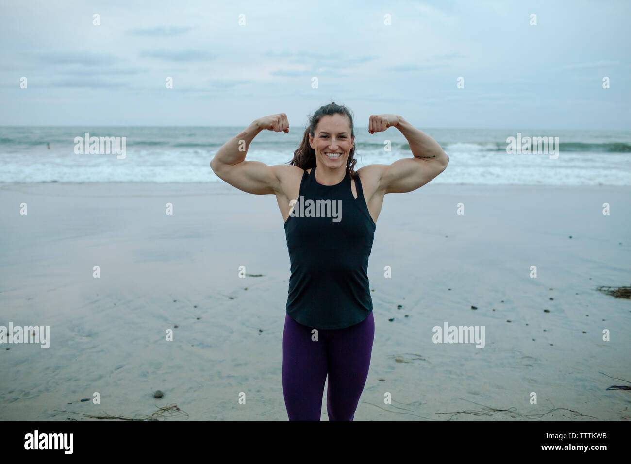 Ritratto di fiducioso muscolare donna costruire muscoli di flessione a beach Foto Stock