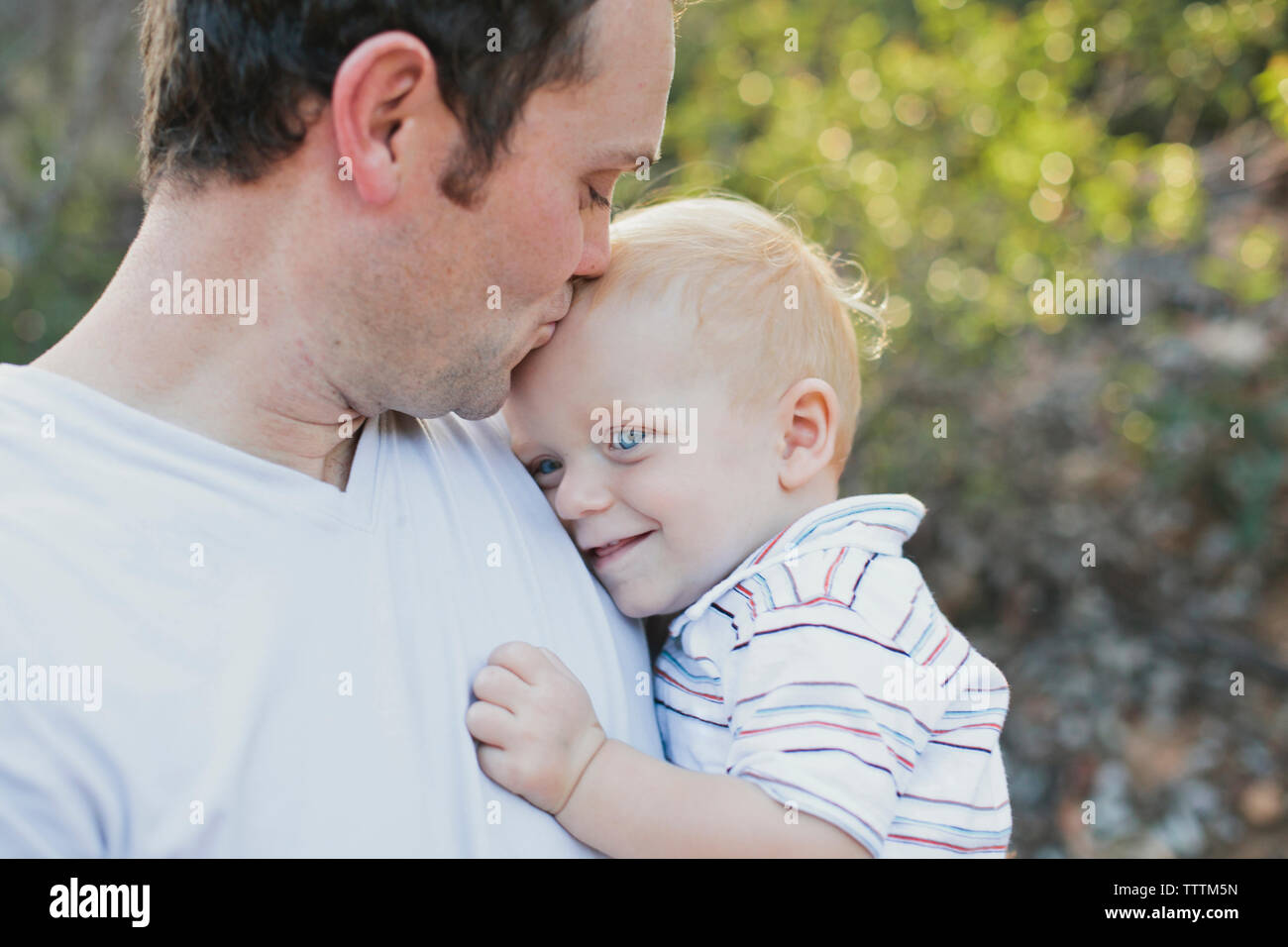 Padre amorevole kissing figlio sulla fronte in posizione di parcheggio Foto Stock