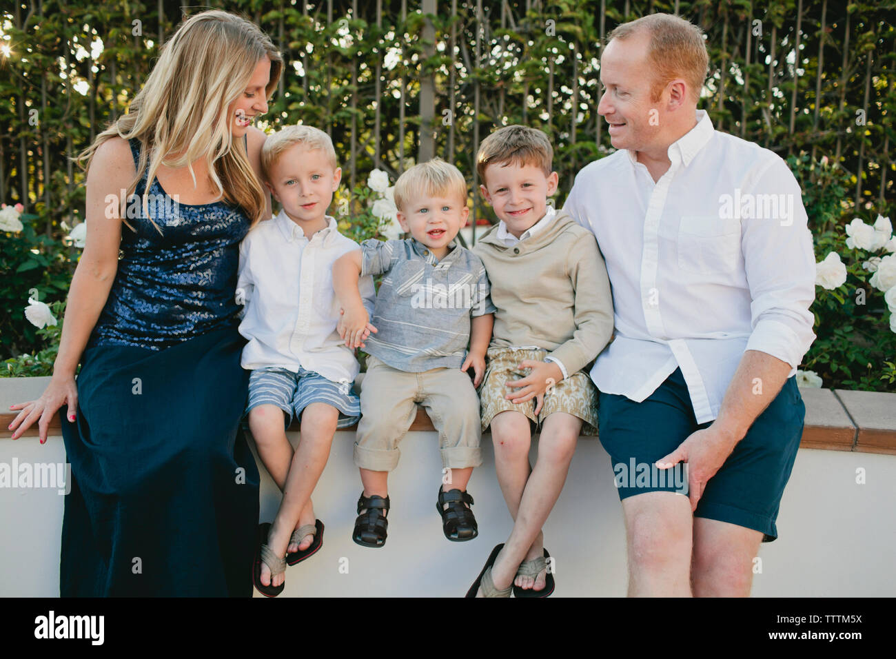 Famiglia allegra seduta sulla parete di ritegno in posizione di parcheggio Foto Stock