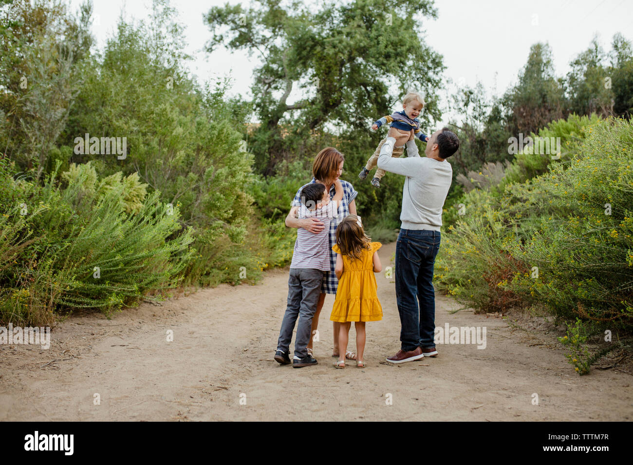 La famiglia felice in piedi sul campo dalle piante Foto Stock