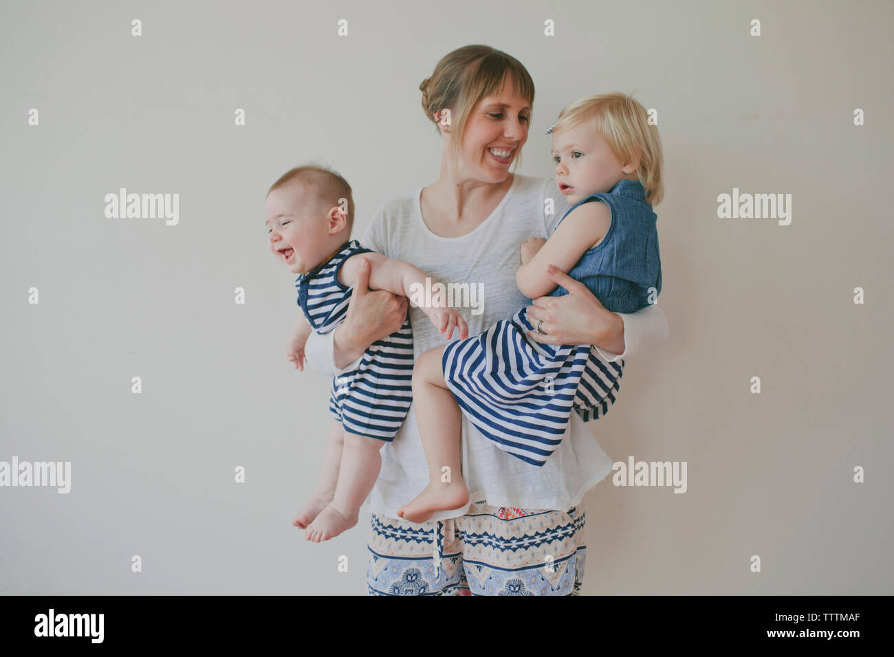 Allegro madre trasportano bambini contro uno sfondo bianco Foto Stock