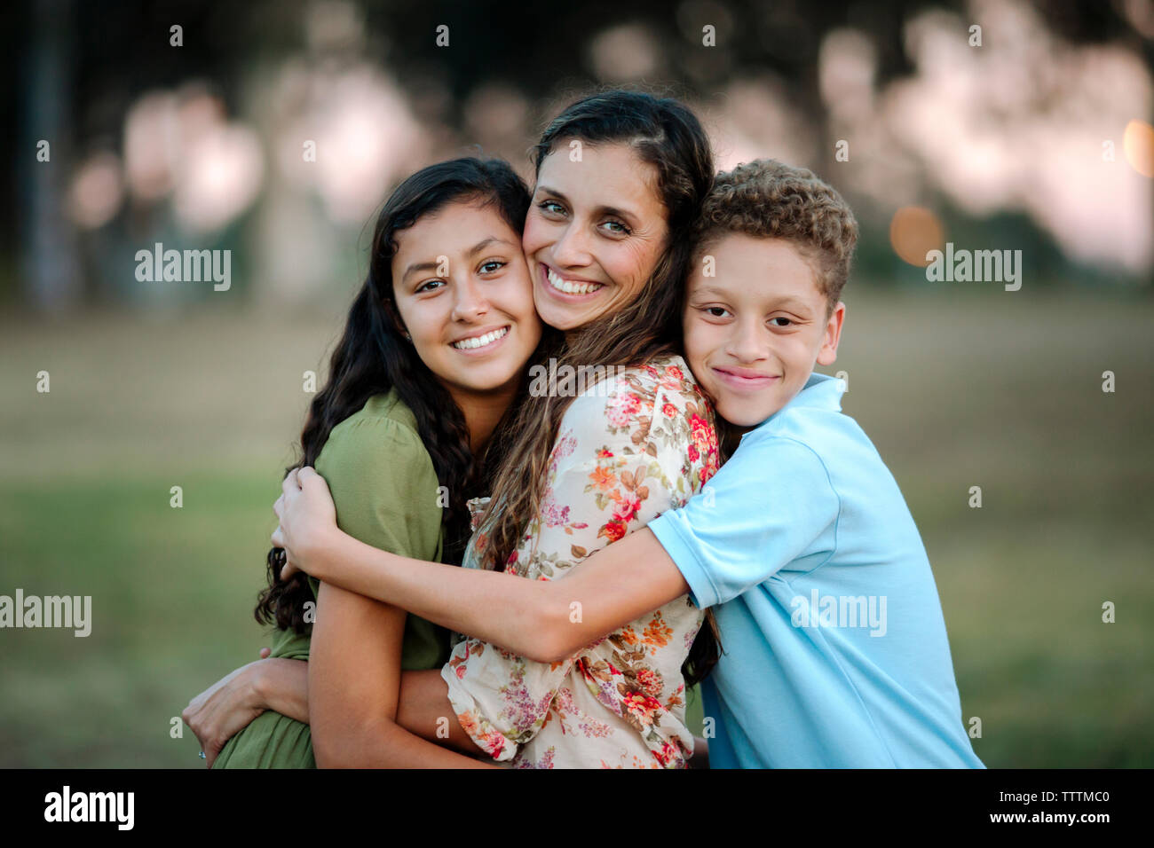 Ritratto di amorevole madre e bambini abbracciando in posizione di parcheggio Foto Stock