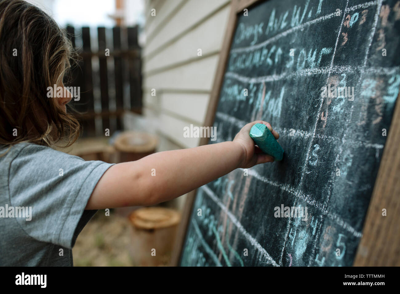 Close-up di ragazza scrivere sulla lavagna con il gesso al cortile Foto Stock