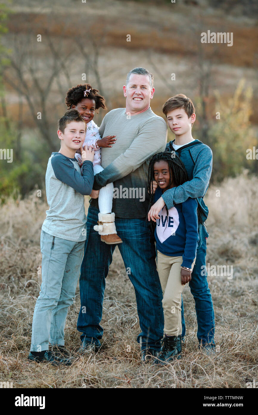 Ritratto di Padre con i bambini in piedi sul campo erboso a forest Foto Stock