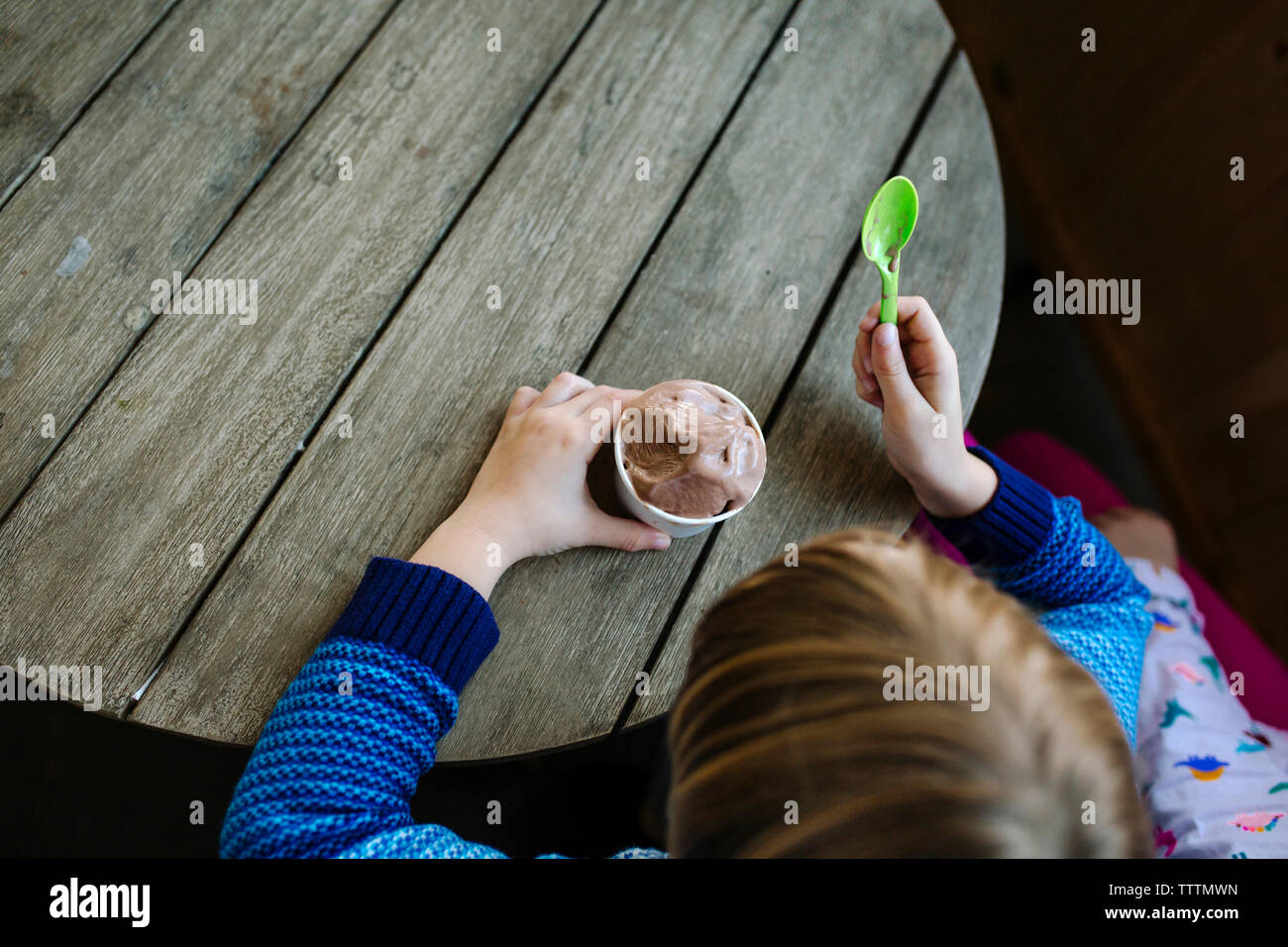 Angolo di Alta Vista del ragazzo a mangiare il gelato seduti a tavola in cafe Foto Stock