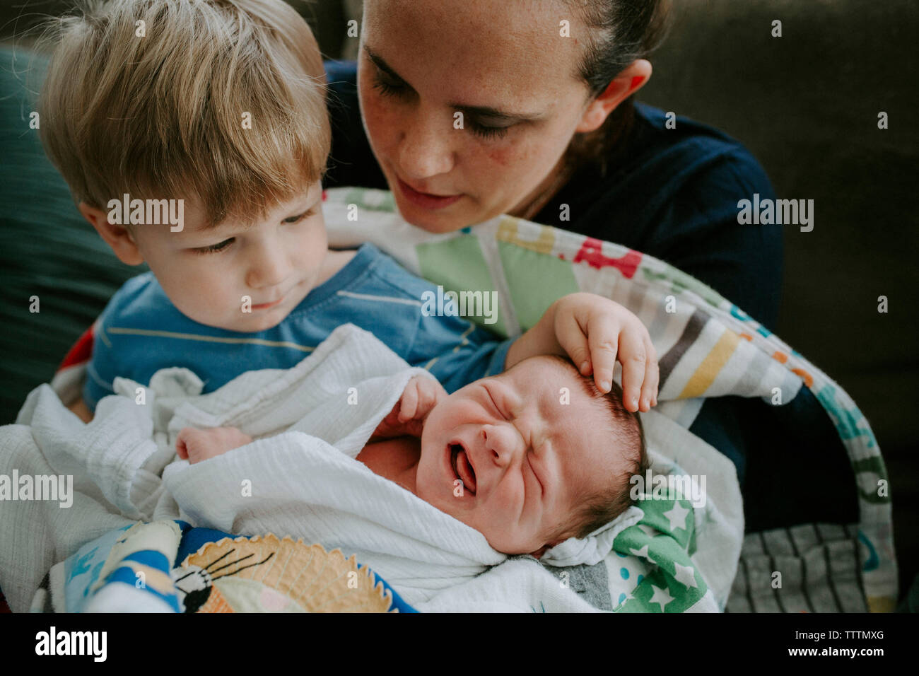 Elevato angolo di visione della madre con figli seduti sul letto di casa Foto Stock