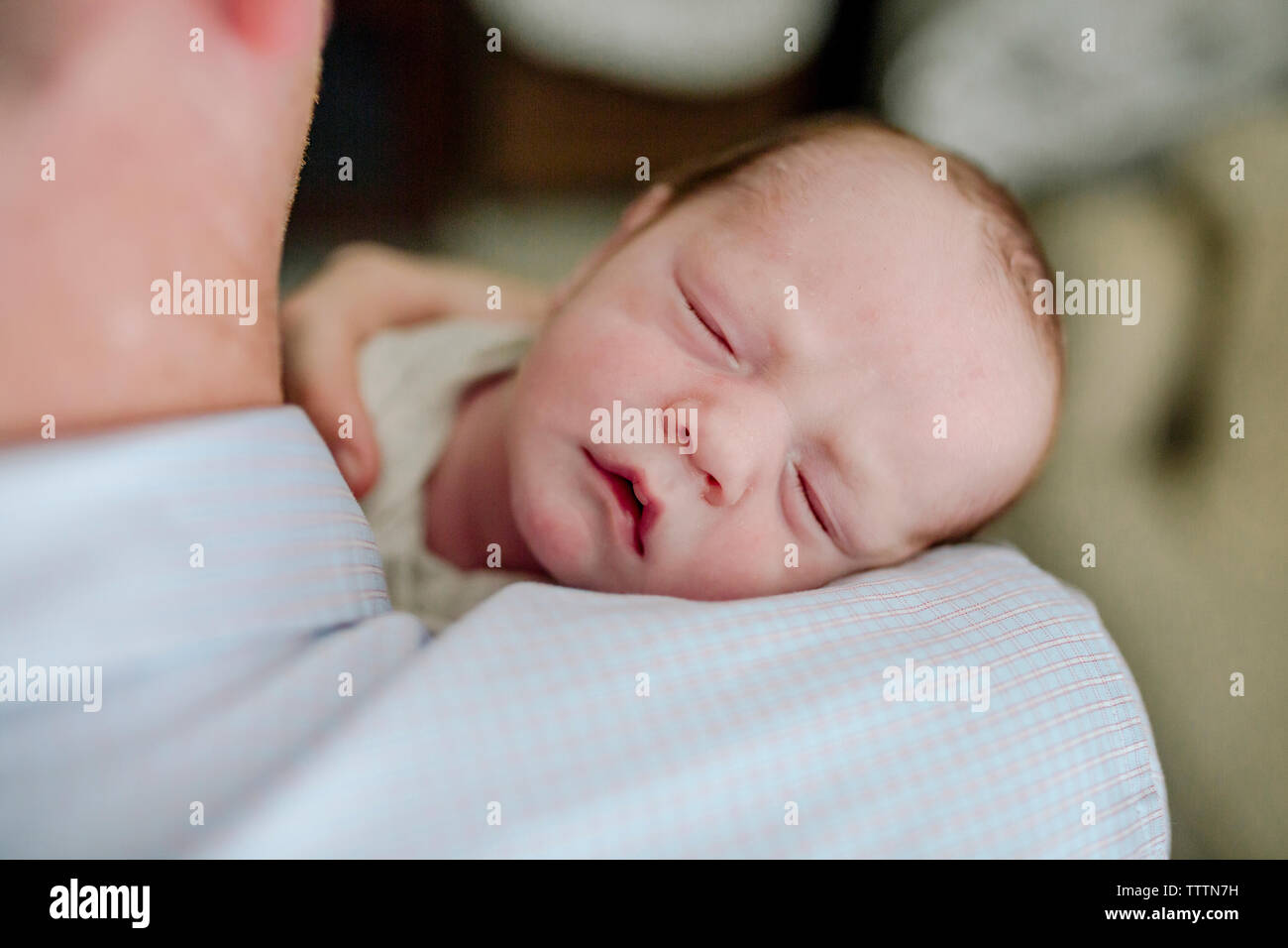 Close-up del padre che porta carino neonato figlio che dorme a casa Foto Stock