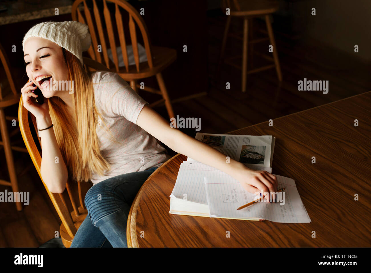 Allegro ragazza adolescente rispondendo alle smart phone mentre lo studio a casa Foto Stock