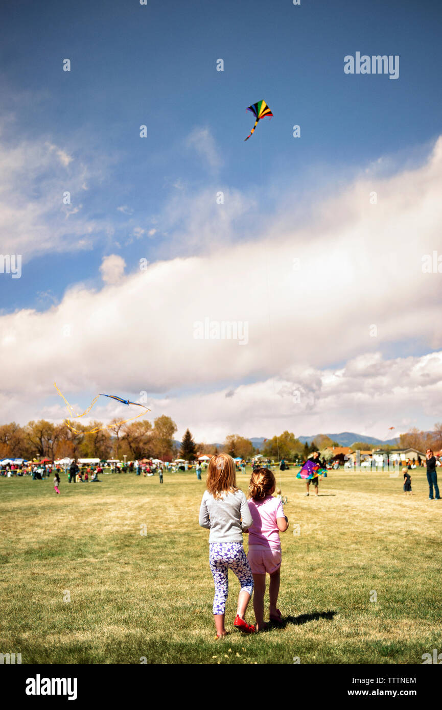 Vista posteriore dei fratelli aquiloni presso il park contro il cielo nuvoloso Foto Stock