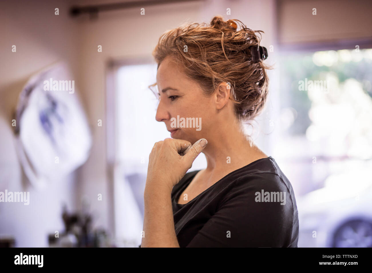 Considerato pittore femmina in piedi con la mano sul mento in art studio Foto Stock