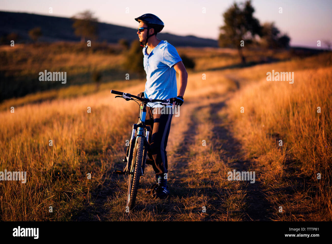 Per tutta la lunghezza del ciclista maschio in piedi con la bicicletta su strada sterrata campo Foto Stock