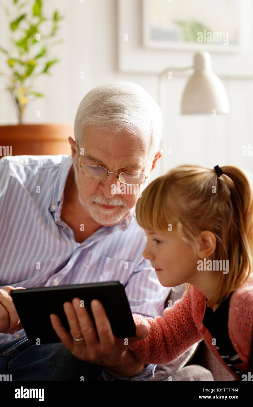 Nonno e nipote utilizzando computer tablet mentre lo studio a casa Foto Stock