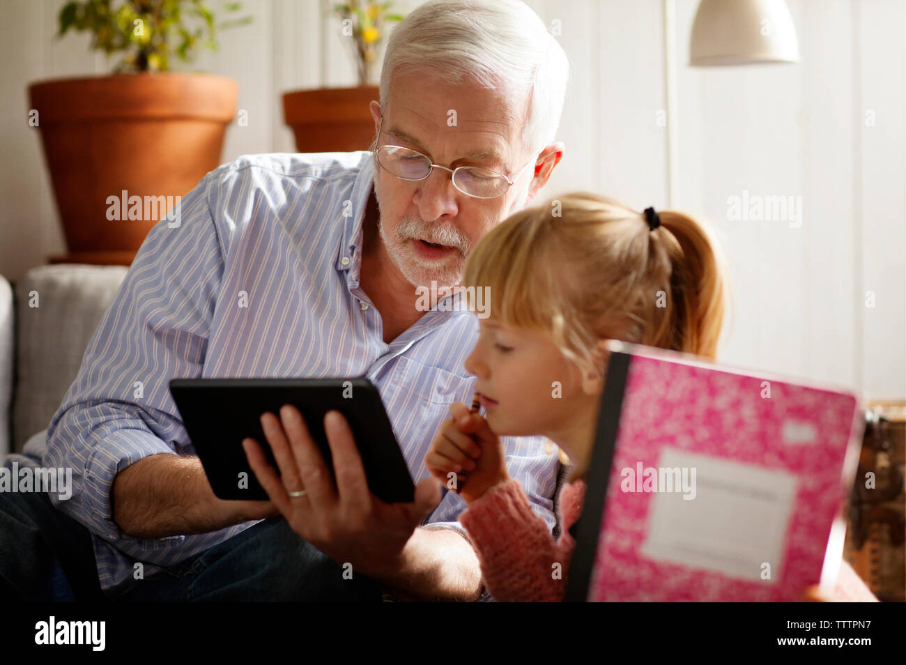 Nonno che mostra computer tavoletta al nipote durante lo studio a casa Foto Stock